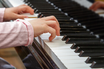 A child learns to play the piano in the lessons at a music school.