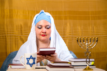 A Jewish woman rabbi of the Reform community in a white veil teaches women to read a prayer.