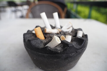 Close up burning cigarette in ashtray on table 