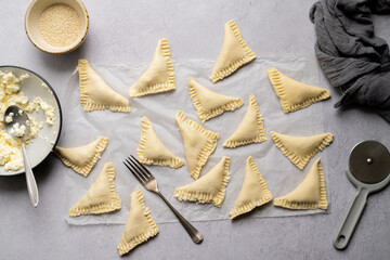 Raw puff pastry triangles, filled with cottage cheese, ready to be baked. © Inga