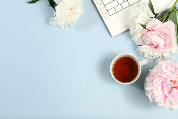 Computer,peony flowers and a cup of coffee on a light table.Desktop of a modern woman, home office....