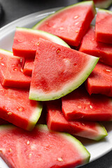 Closeup red juicy watermelon slices in a plate, top view. Summer fresh fruit snack.
