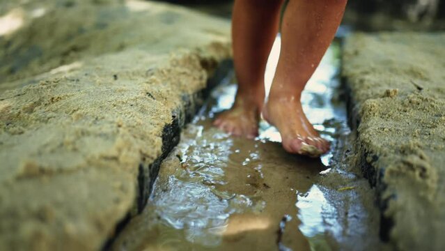 Kid feet stepping in wet muddy sand barefoot. Child closeup foot walking in sand at park outdoors. Childhood lifestyle