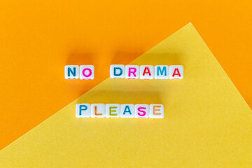 Phrase No drama please made out of square beads on orange and yellow background, flat lay