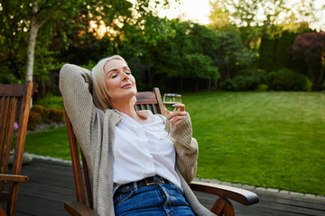 Mature woman enjoys afternoon on terrace with glass of wine