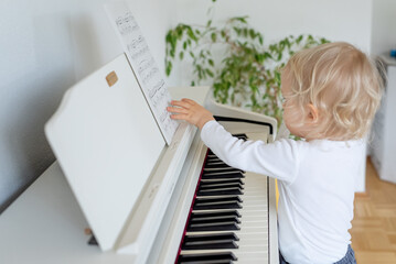 little child playing piano, checking notes	