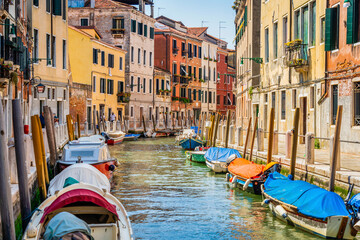 Colorful picturesque Scene from Venice with many boats parked on the narrow water canals.
