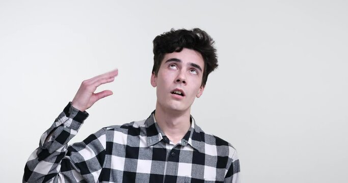 A curly-haired Caucasian man in boredom standing against a pristine white background. He engages in a bored gesture by demonstrating the blah blah motion.