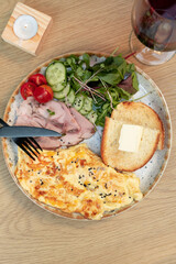 Cutlery with omelette with turkey and vegetables and a glass of wine top view, flat lay