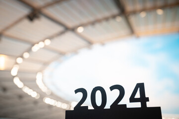 Silhouette of '2024' Sign Inspires as Sports Year Begins, Leading to Summer Games in Paris. Modern Stadium in background.