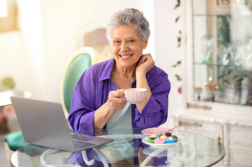 Happy Senior Lady Using Laptop And Having Coffee In Cafe