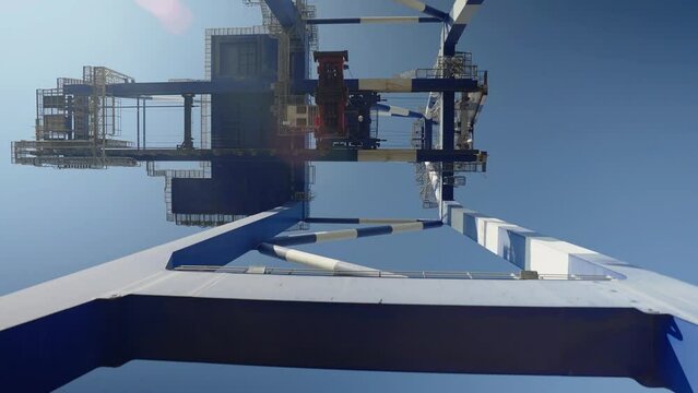 4K drone footage from right underneath port crane platform in sunny daylight stock video.