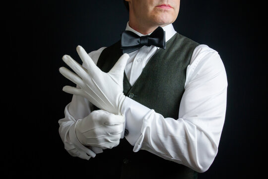 Portrait Of Butler Or Concierge Pulling On White Gloves In A Heroic Manner. Concept Of Service Industry And Professional Hospitality.