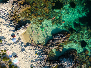 Fototapeta na wymiar Italy, July 2023: aerial view from the drone of a crystalline Caribbean sea with bathers and beach umbrellas at Grotticelle locality near Capo Vaticano, Tropea, Calabria