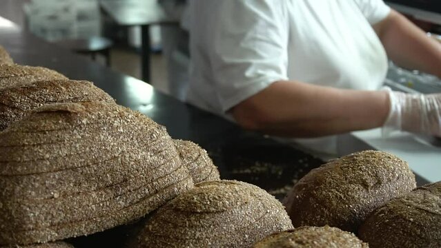A female bakery worker packs sliced ​​bread using a specialized packaging machine. Packaging of bakery products before sending to the store shelves.