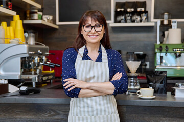 Portrait of female small business owner wearing apron near coffee shop counter