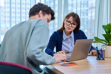 School psychologist supporting guy student, sitting in office of educational building