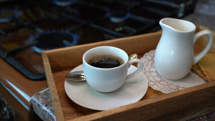 A cup of black tea and milk before gaz stove in country house.