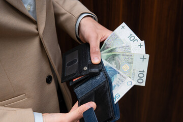 Close-up of Polish money held by a businessman. A man wearing a beige jacket is counting Polish zlotys
