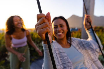 Happy biracial lesbian couple swinging on swing in sunny garden