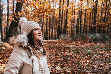 Young woman with wool cap enjoying and breathing the fresh air of an autumn day in the chestnut forest of El Tiemblo, Avila, Spain.