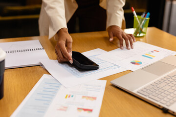 Hands of african american casual businesswoman using smartphone and laptop in office