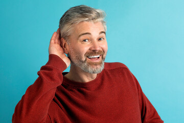 Middle aged man smiling with hand over ear, blue background - obrazy, fototapety, plakaty