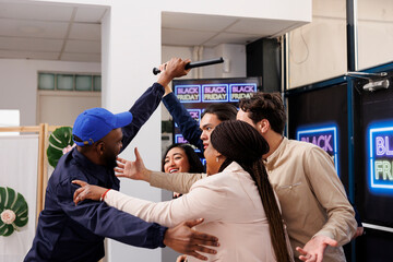 African American man mall security guard pushing back people, trying to hold anxious diverse people shoppers while controlling retail store entrance during Black Friday sales. Violent shopping