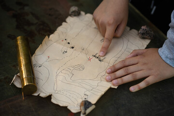 The child's finger points to the buried treasure on the map.A game of pirates in the fresh...