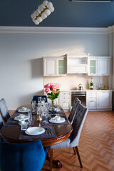 table with dishes and bouquet of roses in the bright kitchen of the living room 