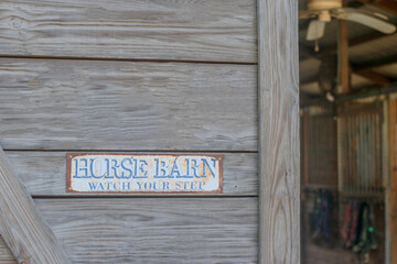 Horse Barn sign on wood plank wall of a barn with view inside