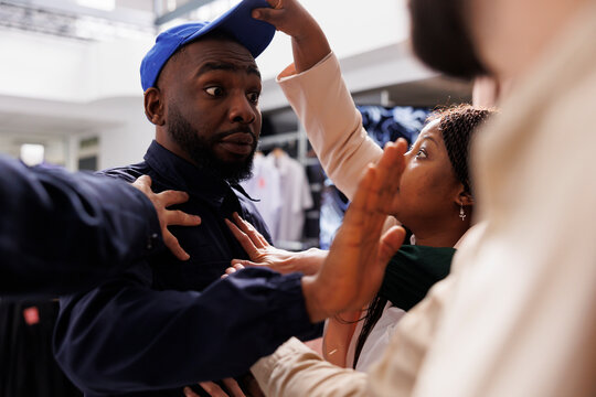 Mad rude diverse people pushing shocked African American man security guard during Black Friday shopping, shoppers going crazy and fighting in store while hunting for bargains