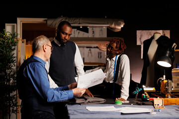 Professional suitmakers consulting with gentleman client on desired custom alterations to sartorial...