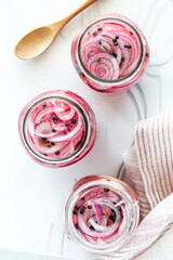 Jars of pickled red onion on a white cutting board.