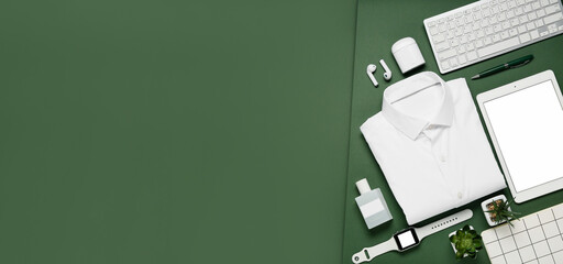 White male shirt, office stationery and modern devices on green background with space for text