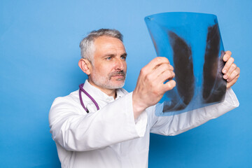 Mature doctor shows his hand on x-ray on a blue background