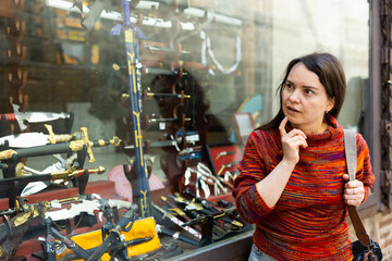 Woman tourist looking for swords and daggers made of famous Toledo steel at local souvenir store