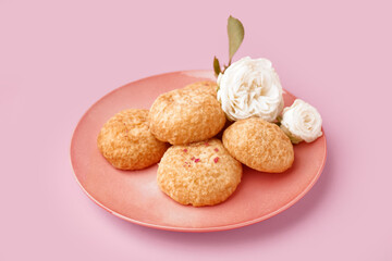 Plate with tasty choux dessert on pink background