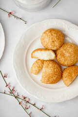 Plate with tasty choux dessert on light background