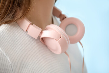 Young woman in headphones listening to music on blue background