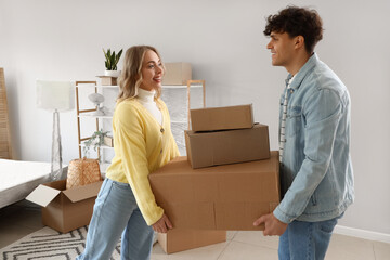 Fototapeta na wymiar Young couple carrying boxes in bedroom on moving day
