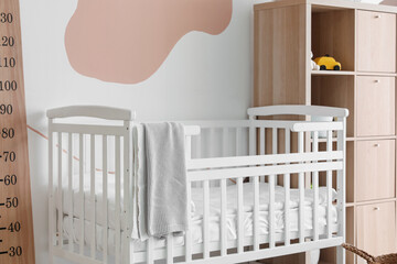 Interior of children's bedroom with crib, stadiometer and shelving unit