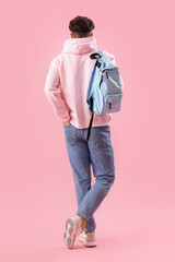 Male student with backpack on pink background, back view