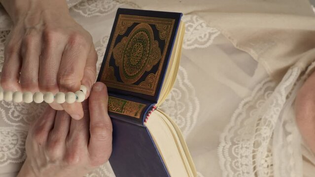 Quran and beads in the hands of a muslim woman