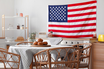 Interior of stylish kitchen with hanging USA flag and tasty buns on table