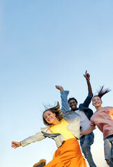 Group of happy multiracial  friends smiling and jumping over blue background - Concept of happiness, freedom, motion,  and friendship.  - obrazy, fototapety, plakaty