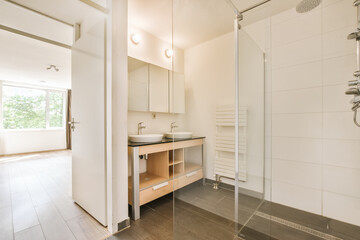 a modern bathroom with white walls and wood flooring, including a shower stall in the middle part of the room