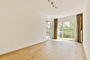 an empty living room with wood flooring and sliding glass doors leading out to the patio area in...
