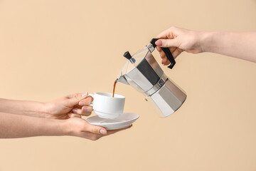 Woman pouring espresso from geyser coffee maker into cup on beige background