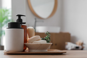 Soap bars, dispensers and shaving brush on wooden table in bathroom